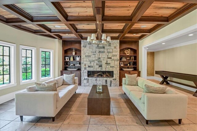 living room with a stone fireplace, light tile patterned floors, built in shelves, and coffered ceiling