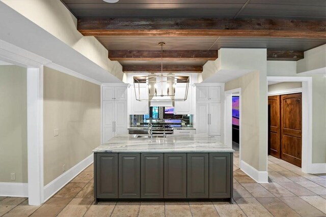 kitchen featuring gray cabinetry, light tile patterned floors, beamed ceiling, and light stone countertops