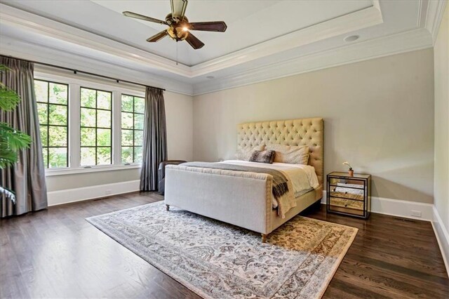 bedroom featuring ceiling fan, a raised ceiling, dark hardwood / wood-style floors, and ornamental molding