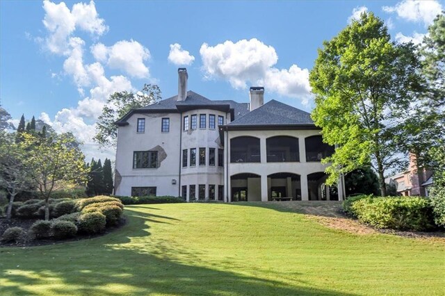 rear view of house featuring a lawn and a sunroom