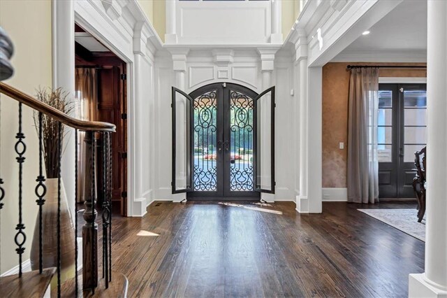 entrance foyer featuring dark wood-type flooring, ornamental molding, decorative columns, and french doors