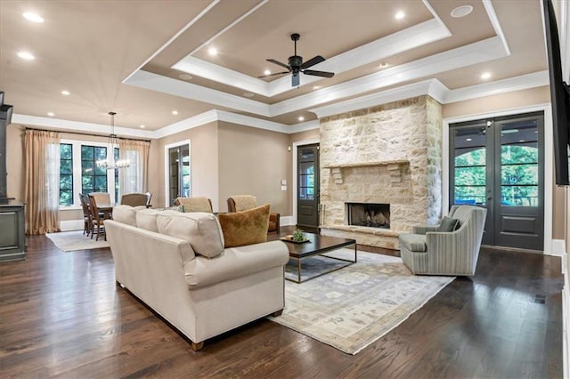 living room with a wealth of natural light, dark hardwood / wood-style floors, a fireplace, and a tray ceiling