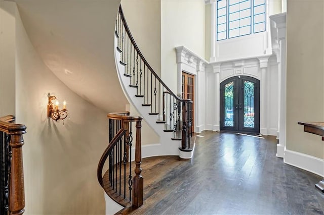 entryway with a high ceiling, wood-type flooring, french doors, and an inviting chandelier