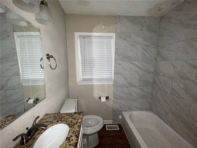 bathroom with a tub to relax in, vanity, and toilet