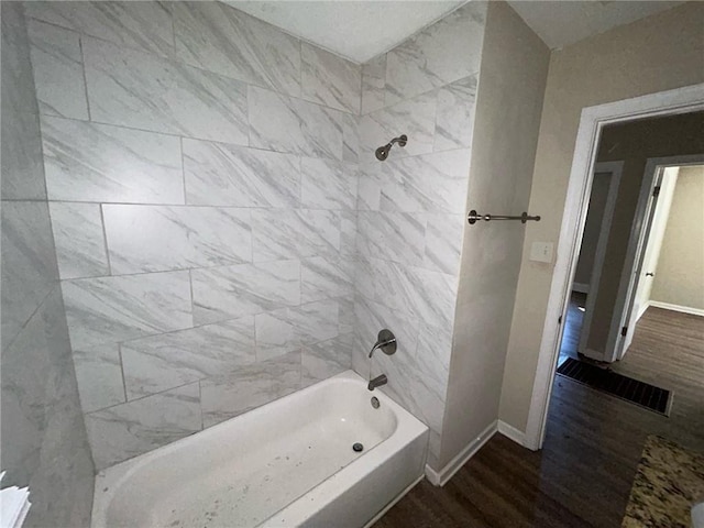 bathroom featuring wood-type flooring and tiled shower / bath