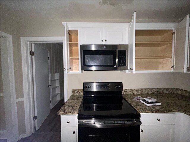 kitchen with white cabinets, black / electric stove, and dark stone counters