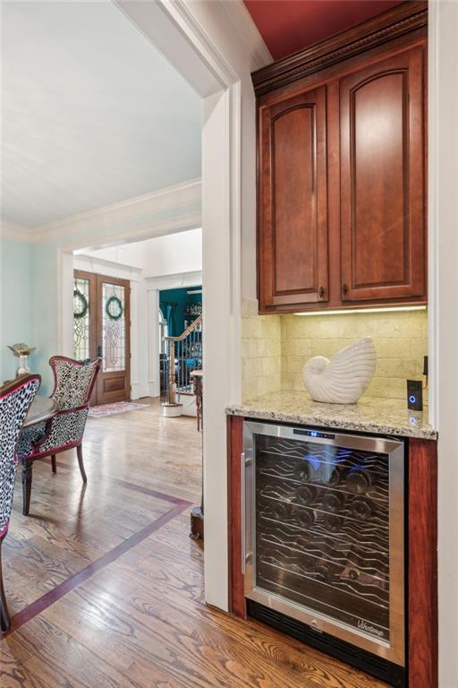 3215 Kylee Dawn Cir, Lawrenceville, GA 30045 - bar with tasteful backsplash, wood finished floors, ornamental molding, a bar, and wine cooler