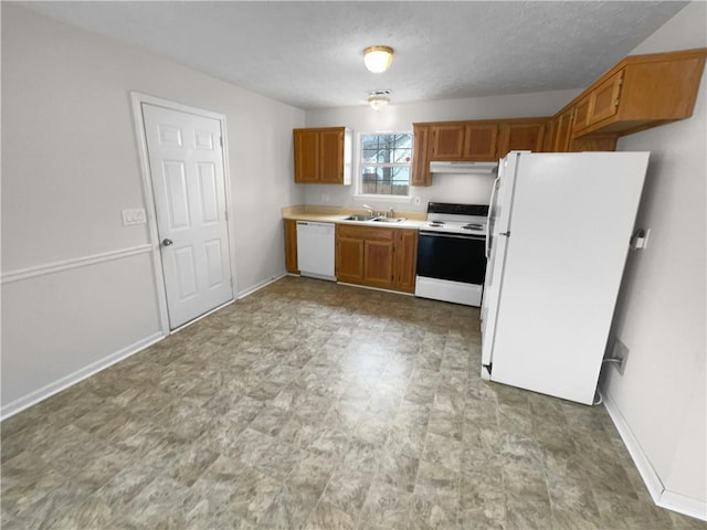 kitchen featuring light countertops, white appliances, brown cabinetry, and a sink