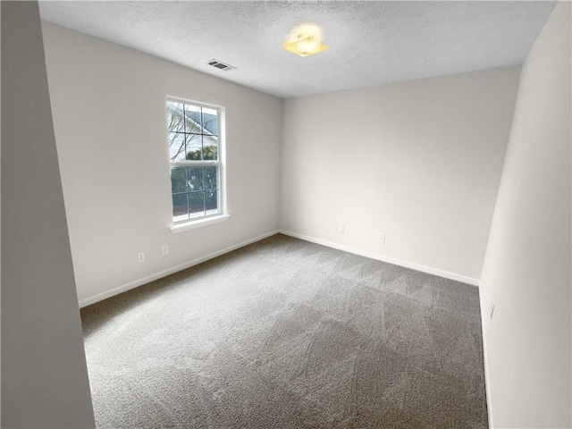 unfurnished room with a textured ceiling, carpet, visible vents, and baseboards