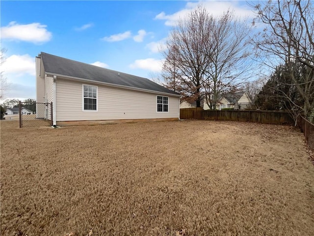 back of property with a fenced backyard and a lawn