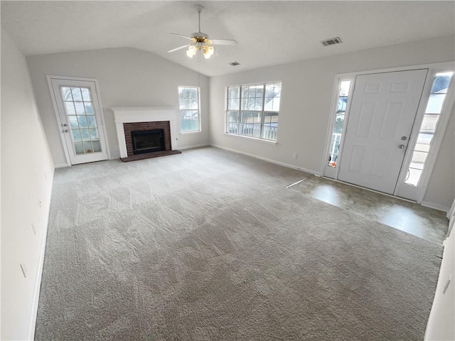 unfurnished living room with visible vents, a ceiling fan, light colored carpet, vaulted ceiling, and a brick fireplace