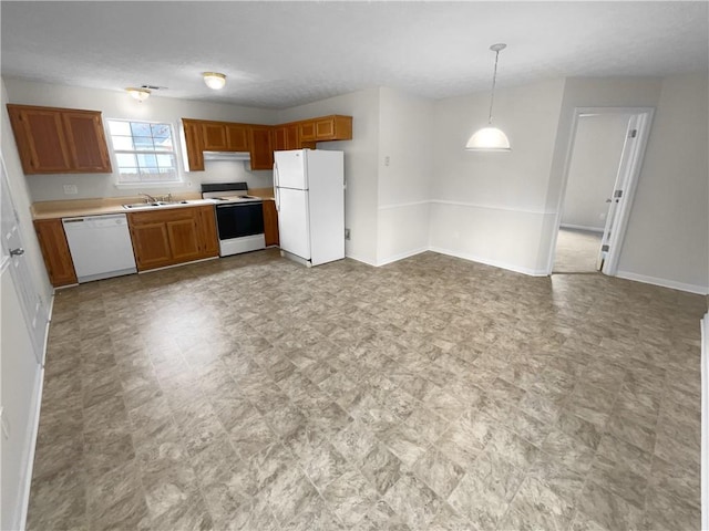 kitchen with brown cabinets, light countertops, hanging light fixtures, a sink, and white appliances