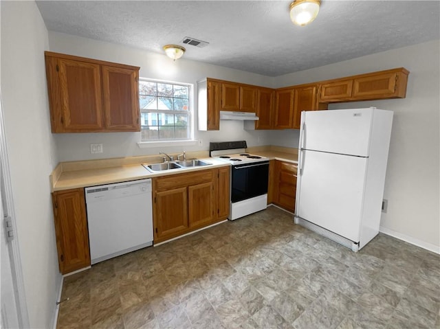kitchen with brown cabinets, light countertops, a sink, white appliances, and under cabinet range hood