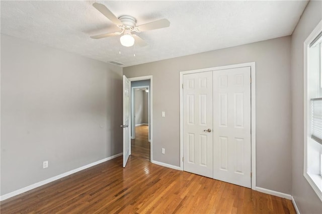 2201 Colonial Oak Way, Stone Mountain, GA 30087 - unfurnished bedroom with wood finished floors, baseboards, a closet, ceiling fan, and multiple windows