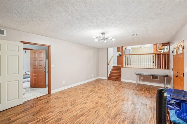 2201 Colonial Oak Way, Stone Mountain, GA 30087 - unfurnished living room with wood finished floors, stairway, a chandelier, baseboards, and a textured ceiling
