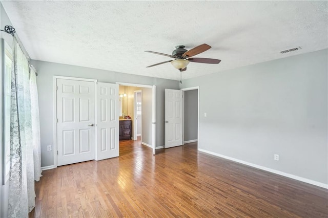 2201 Colonial Oak Way, Stone Mountain, GA 30087 - unfurnished bedroom featuring a textured ceiling, baseboards, wood finished floors, and a ceiling fan