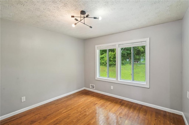 2201 Colonial Oak Way, Stone Mountain, GA 30087 - unfurnished room with hardwood / wood-style floors, baseboards, a chandelier, and a textured ceiling