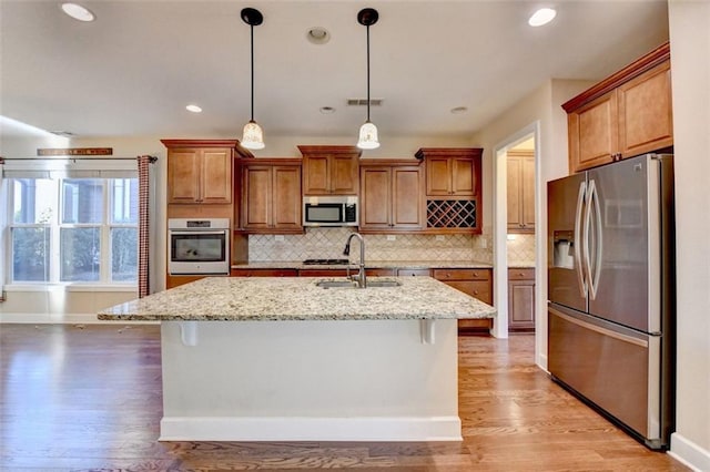 kitchen with sink, stainless steel appliances, a kitchen island with sink, and a kitchen bar