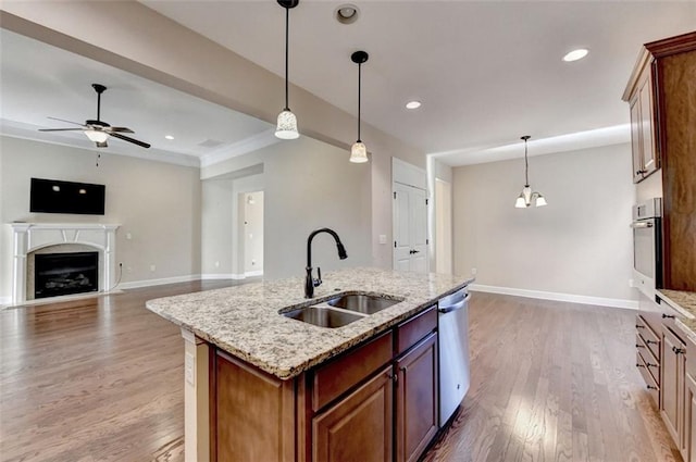 kitchen featuring a fireplace, light wood finished floors, appliances with stainless steel finishes, a ceiling fan, and a sink