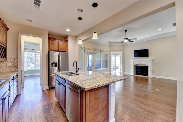 kitchen featuring visible vents, decorative backsplash, appliances with stainless steel finishes, a fireplace, and a sink