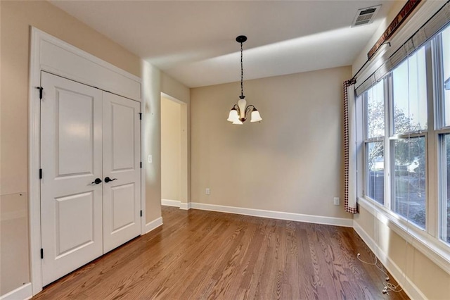 empty room with a notable chandelier and wood-type flooring