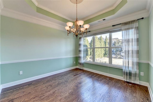 empty room featuring dark hardwood / wood-style floors, ornamental molding, a raised ceiling, and a notable chandelier