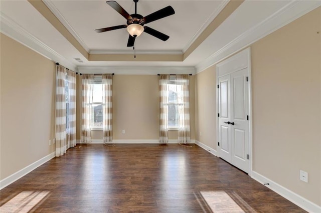 spare room featuring ceiling fan, dark wood-type flooring, a tray ceiling, and crown molding