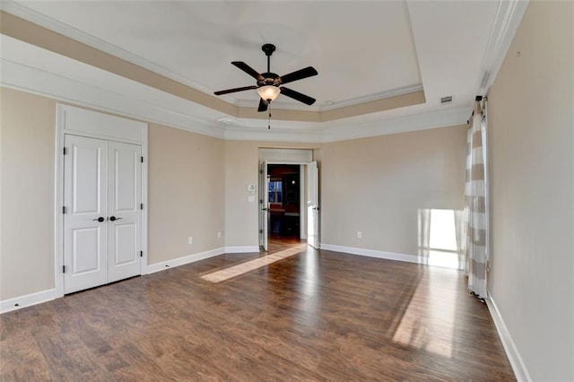 unfurnished room featuring a raised ceiling, crown molding, baseboards, and wood finished floors