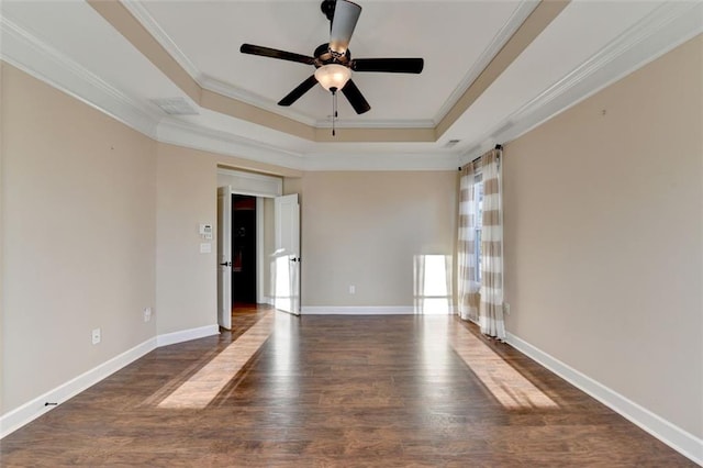 empty room with ornamental molding, dark hardwood / wood-style flooring, ceiling fan, and a raised ceiling