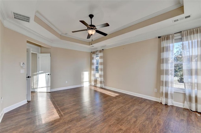 empty room with ceiling fan, crown molding, dark hardwood / wood-style floors, and a raised ceiling