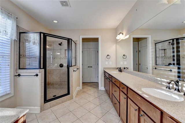 bathroom with walk in shower, vanity, and tile patterned flooring