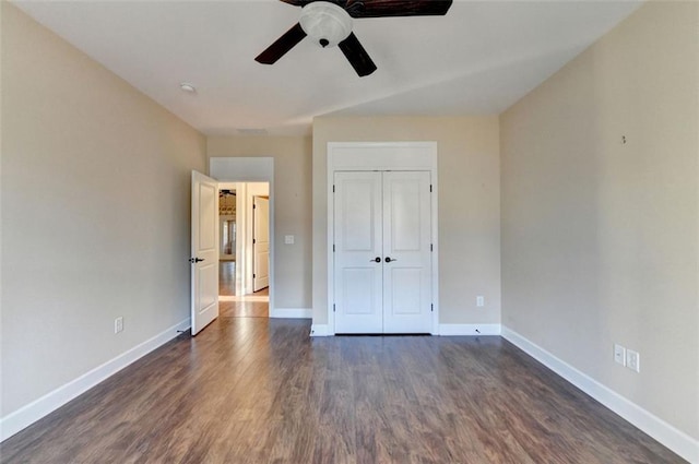 unfurnished bedroom with ceiling fan, a closet, baseboards, and dark wood-type flooring