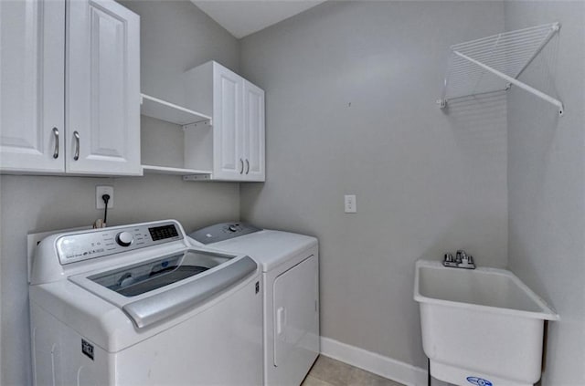 washroom with sink, cabinets, washer and clothes dryer, and light tile patterned floors