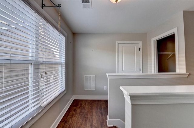 hallway with baseboards, visible vents, and dark wood-style flooring