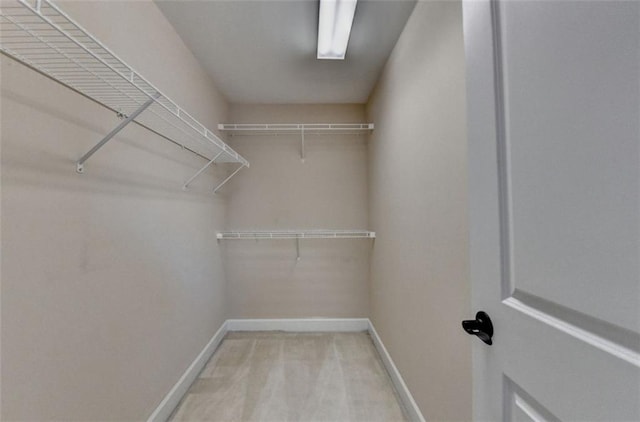 walk in closet featuring light colored carpet