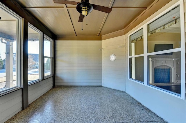 unfurnished sunroom featuring ceiling fan and a healthy amount of sunlight