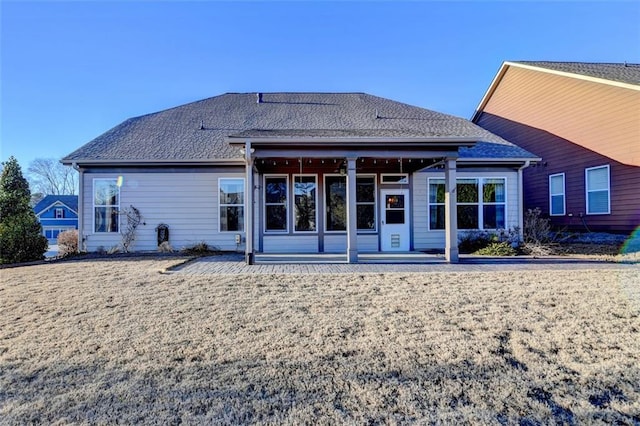 back of house featuring a patio, roof with shingles, and a lawn