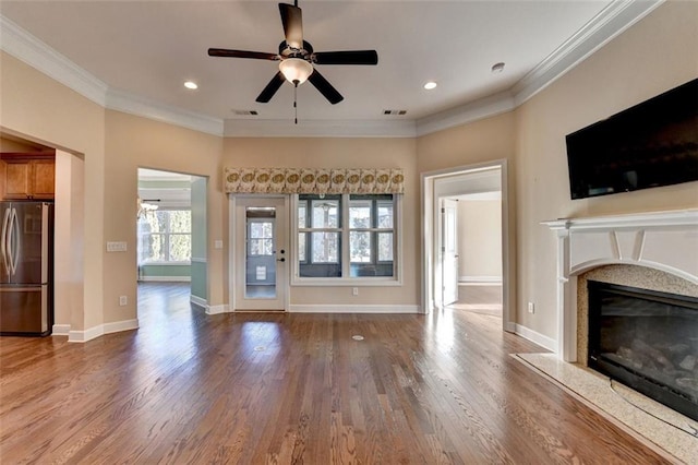 unfurnished living room featuring wood finished floors, visible vents, a high end fireplace, baseboards, and ornamental molding