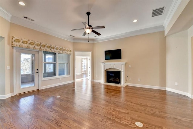 unfurnished living room featuring ornamental molding, a glass covered fireplace, visible vents, and wood finished floors