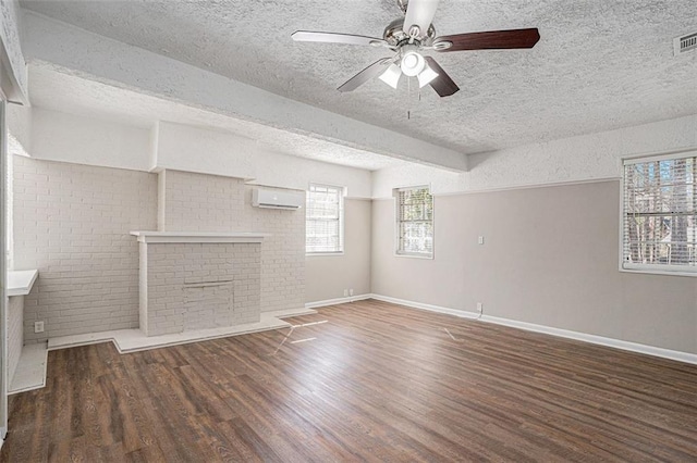 unfurnished living room with a textured ceiling, an AC wall unit, wood finished floors, and baseboards