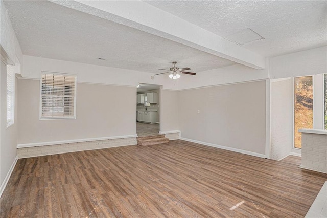 spare room featuring beam ceiling, ceiling fan, a textured ceiling, and wood finished floors