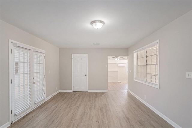 unfurnished bedroom featuring access to outside, multiple windows, light wood-style flooring, and baseboards