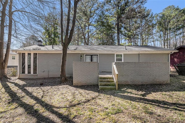 back of house with a chimney and brick siding