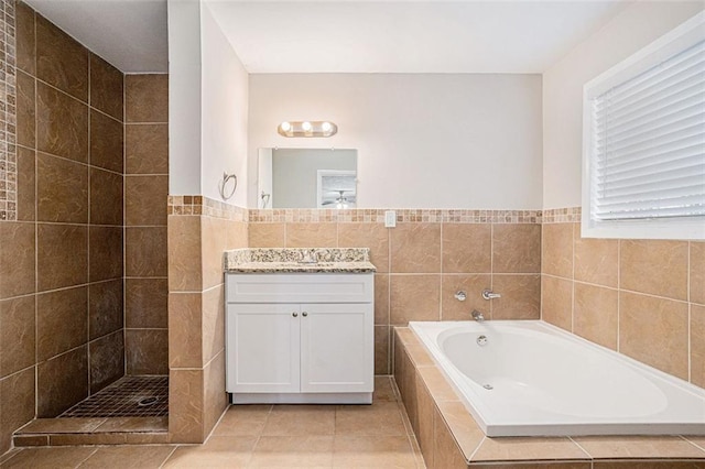 bathroom featuring tiled shower, a bath, tile patterned floors, vanity, and tile walls