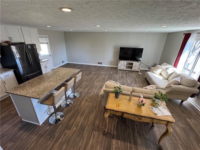 living room featuring a healthy amount of sunlight, baseboards, dark wood-type flooring, and recessed lighting