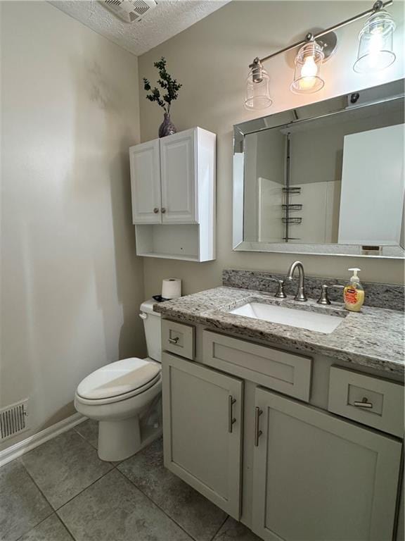 bathroom with a textured ceiling, tile patterned flooring, toilet, vanity, and visible vents