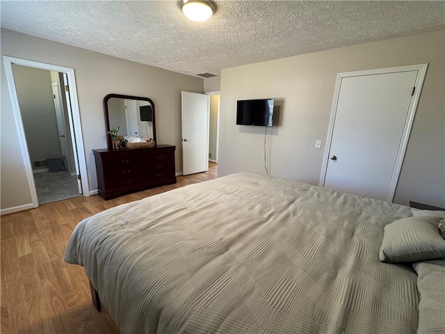 bedroom with visible vents, a textured ceiling, and wood finished floors