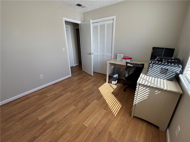 office area featuring light wood-style flooring, visible vents, and baseboards