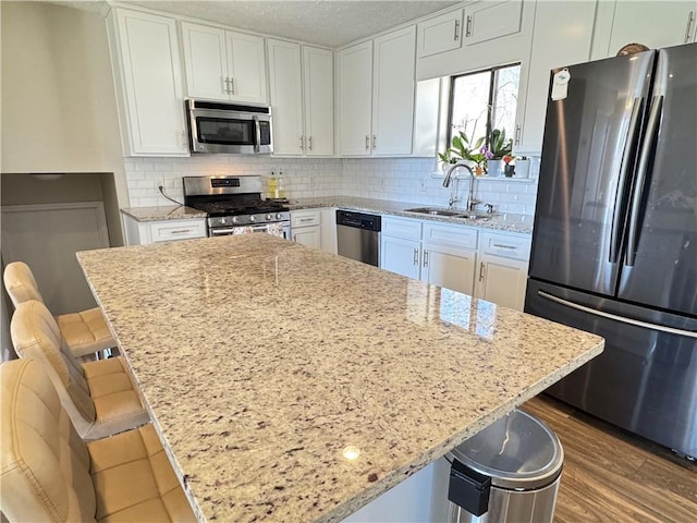 kitchen featuring appliances with stainless steel finishes, white cabinets, a sink, and decorative backsplash