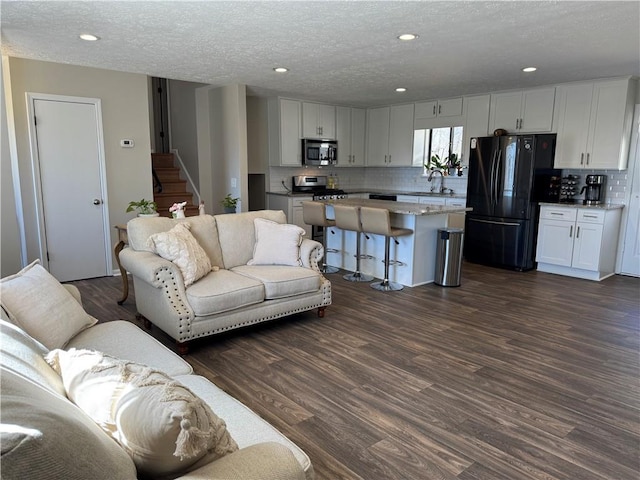 living area featuring stairs, dark wood-type flooring, a textured ceiling, and recessed lighting